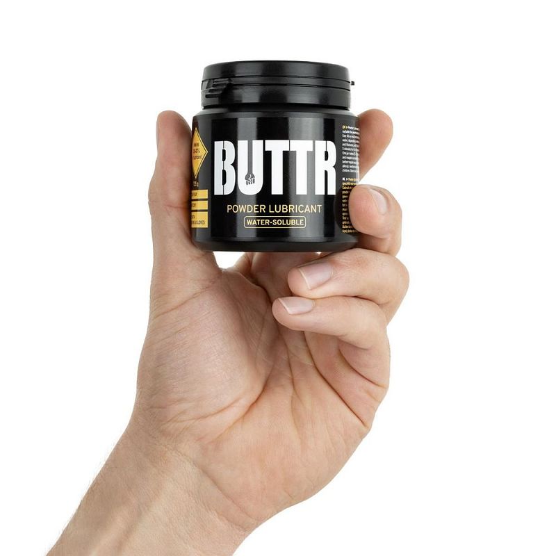 Hand holding the compact BUTTR Powder Lube 135g tub